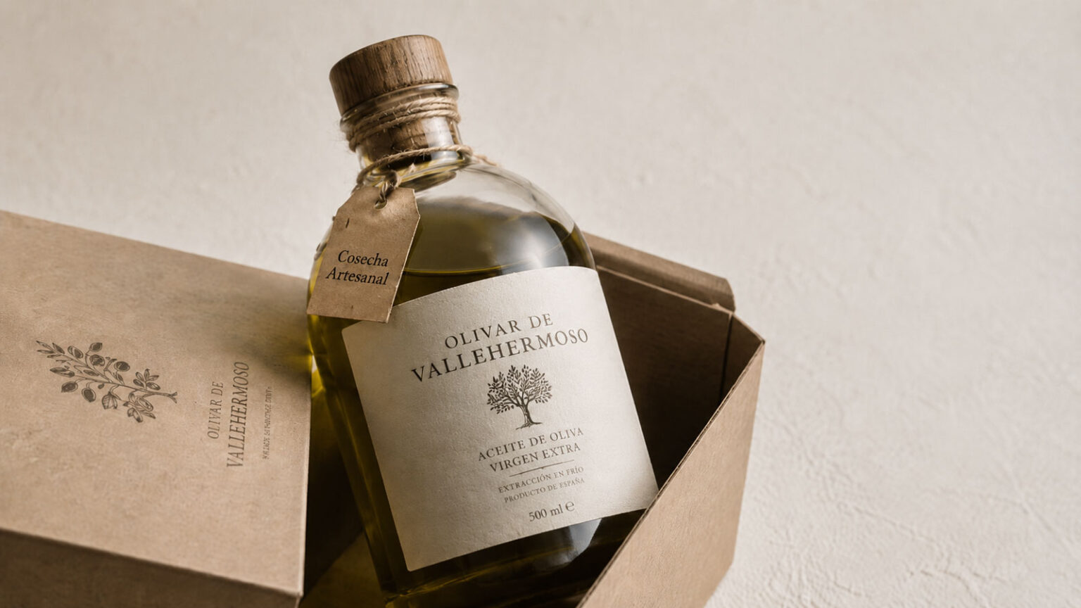 Botella de aceite de oliva virgen extra en envase de vidrio redondo con tapón de madera y etiqueta minimalista, presentada en caja de cartón kraft con logotipo impreso sobre fondo neutro.
